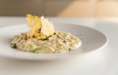 A chef in crisp white attire delicately plating a signature risotto with precision.