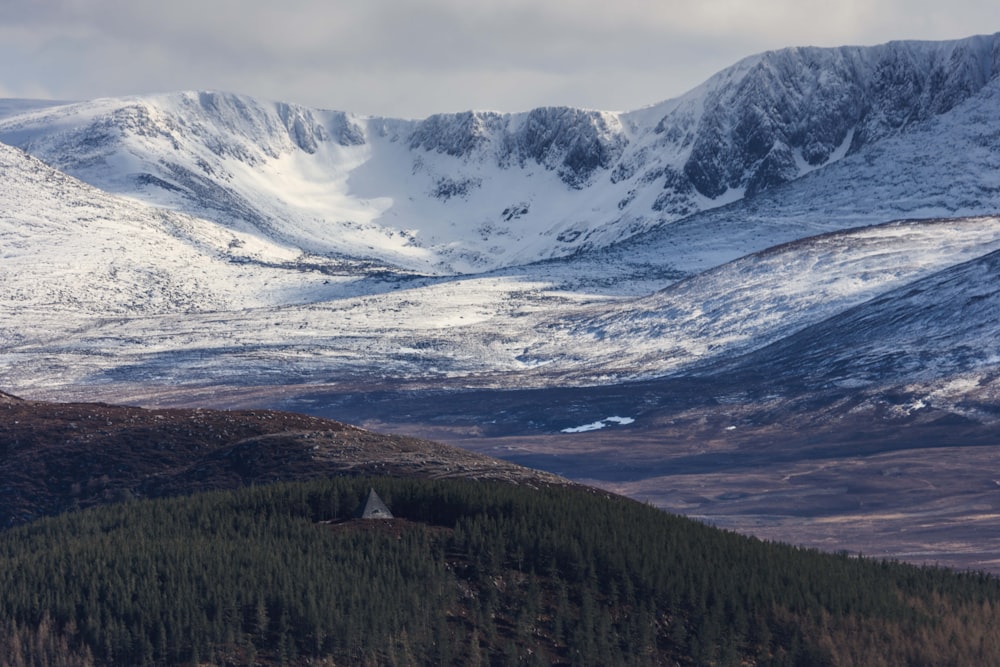 a snowy mountain range with a house in the foreground