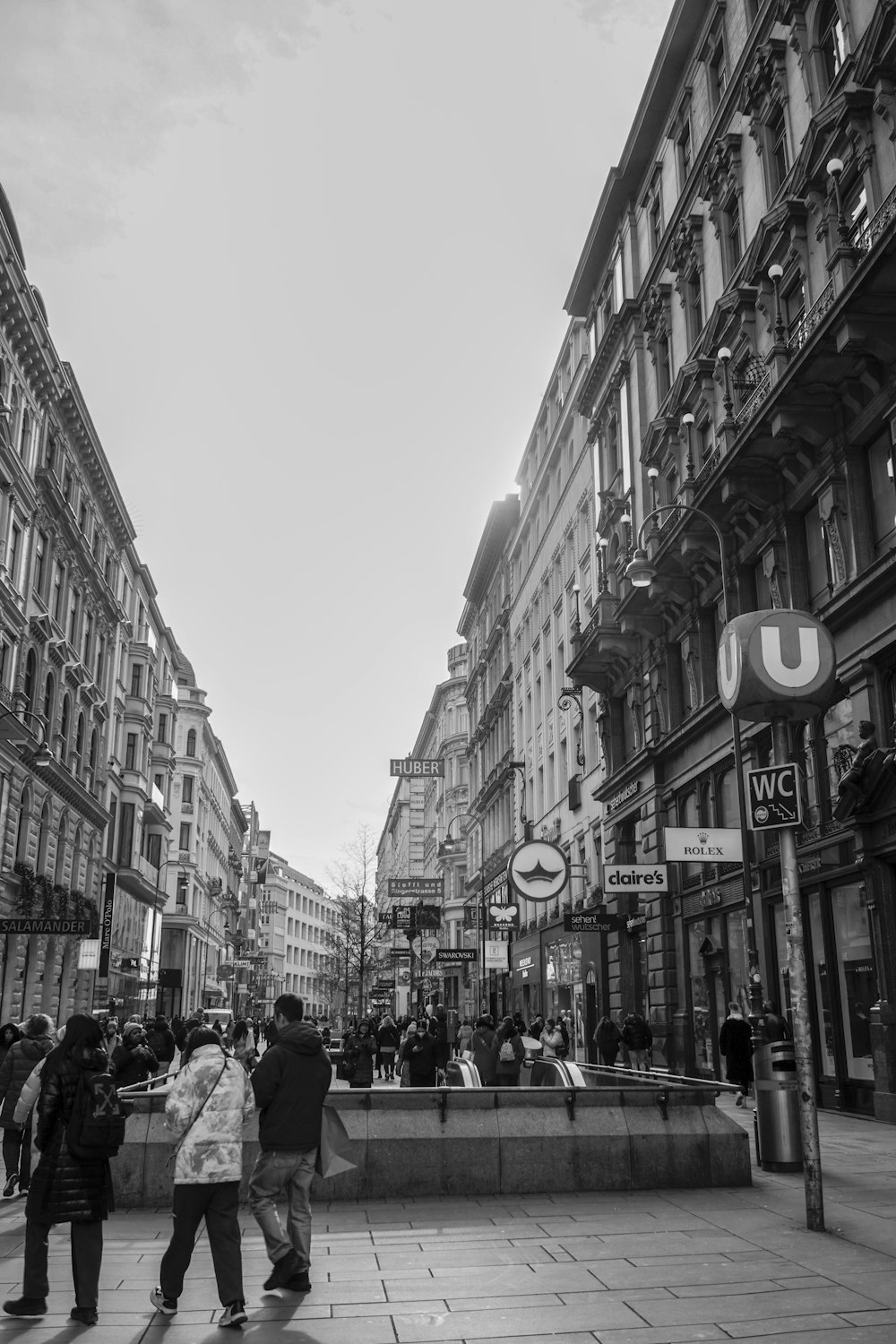 a group of people walking down a street next to tall buildings