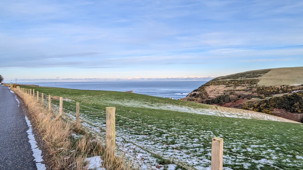 a road with snow on the ground next to the ocean