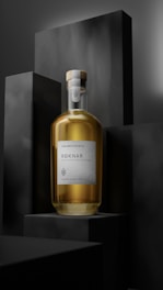 A bottle of Roknar Maryland Style Rye Whiskey is placed prominently against a dark, minimalist background, featuring block-like shapes. The bottle is filled with an amber liquid and has a simple, elegant label.
