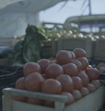 Close-up of vibrant fresh tomatoes stacked in wooden crates at a bustling market.