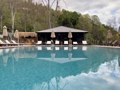 a large swimming pool with lounge chairs and umbrellas