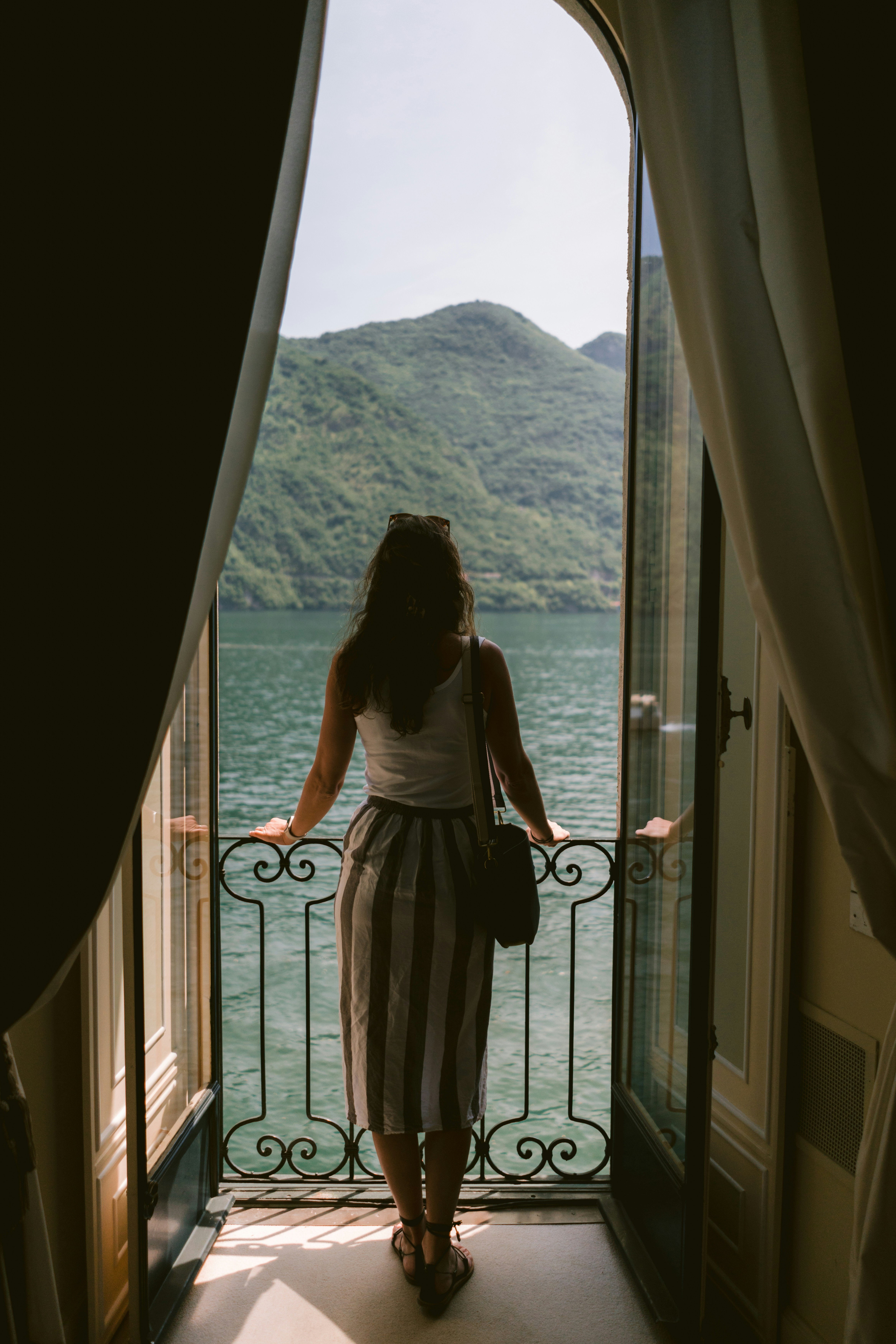a woman looking out of a window at a body of water