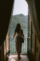 a woman looking out of a window at a body of water