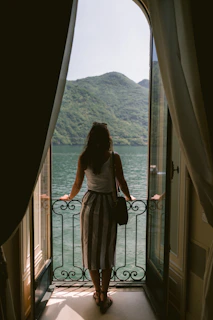 a woman looking out of a window at a body of water