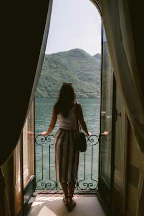 a woman looking out of a window at a body of water