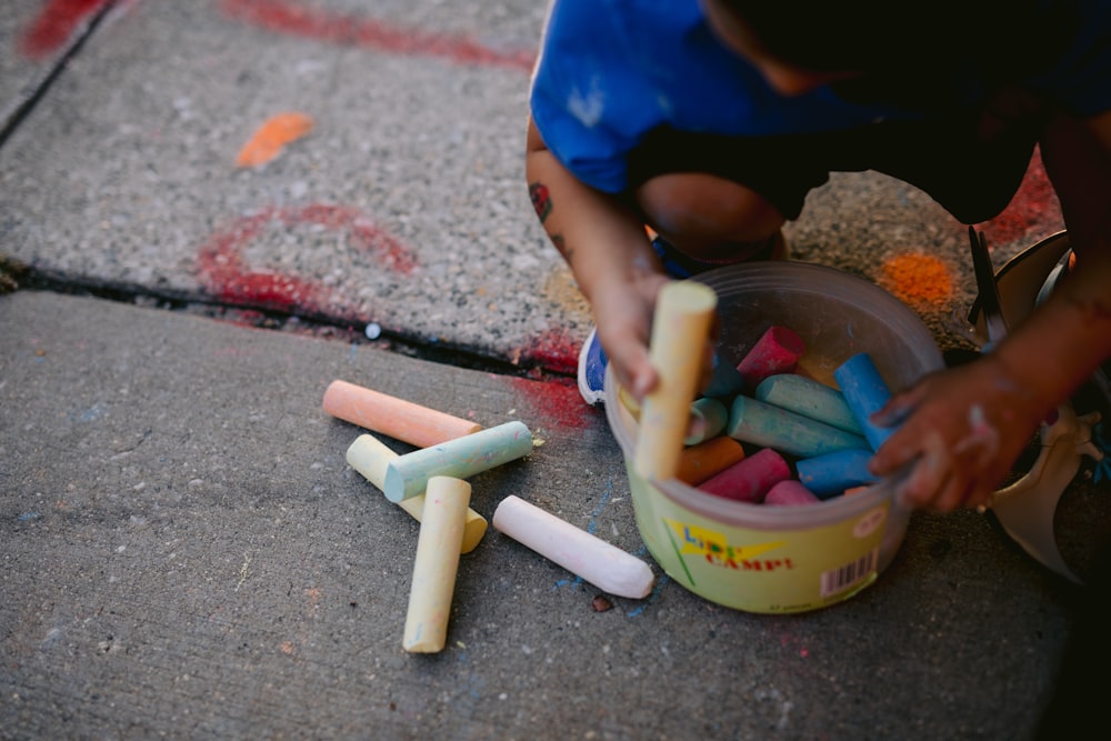 a child is playing with crayons on the sidewalk