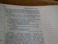 A close-up view of an open book showing text from the Bible, specifically Jeremiah 3:22, with printed lines and numbers visible on a slightly curved page.