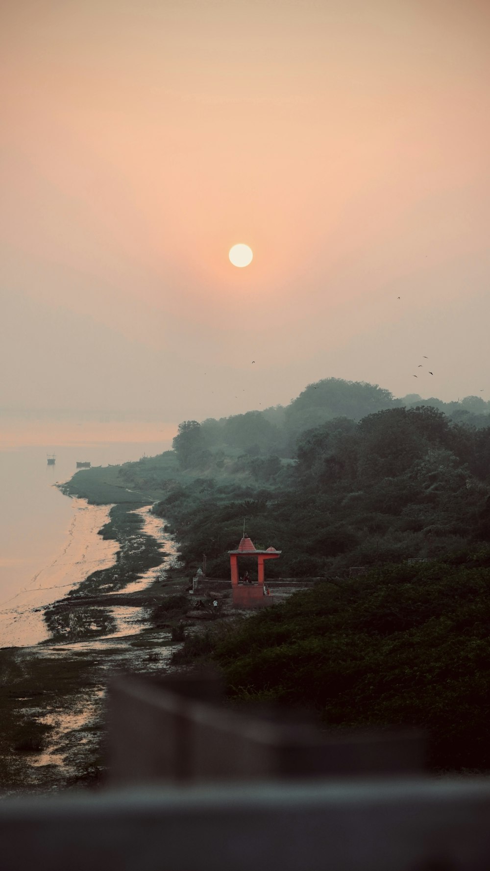 the sun is setting over the water and a beach