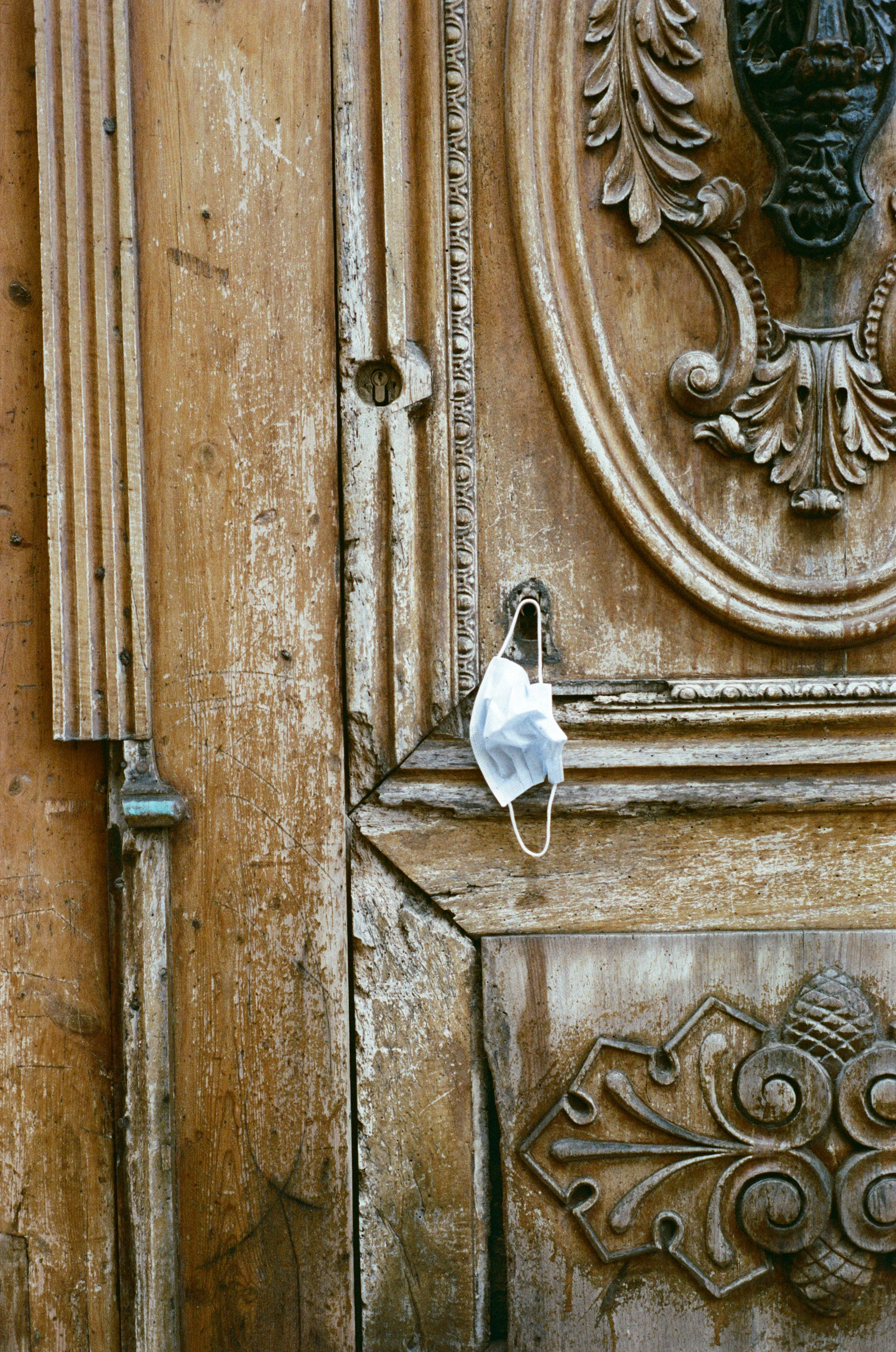 Close-up of a weathered wooden door with intricate carvings, telling stories of a quaint village visited during travels.