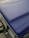 A close-up view of a matte textured blue car hood with part of the front grille and headlight visible. The surface appears even and non-reflective, indicating a durable finish.