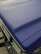 A close-up view of a matte textured blue car hood with part of the front grille and headlight visible. The surface appears even and non-reflective, indicating a durable finish.
