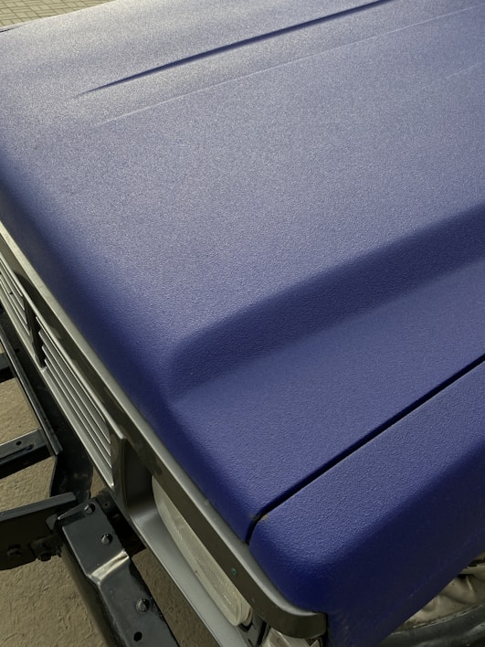 Close-up of matte black car wrap foil being applied smoothly on a vehicle hood.