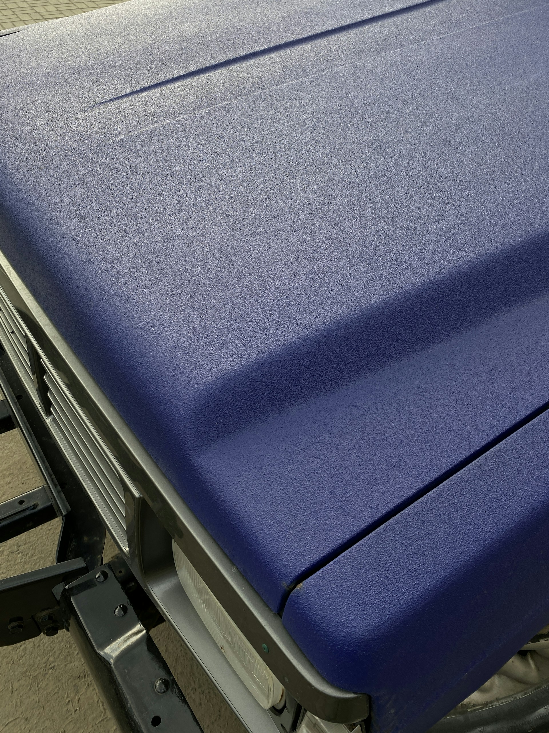 Close-up of a hand smoothly applying a matte blue hentair wrapping film onto a car door, highlighting the film's texture and flexibility.