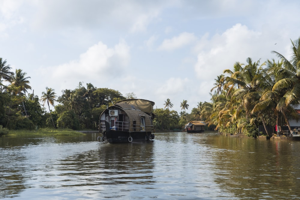 a house boat traveling down a river surrounded by palm trees