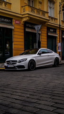 A sleek red 2025 Mercedes Classe C AMG parked elegantly on a quiet street in the Yvelines.