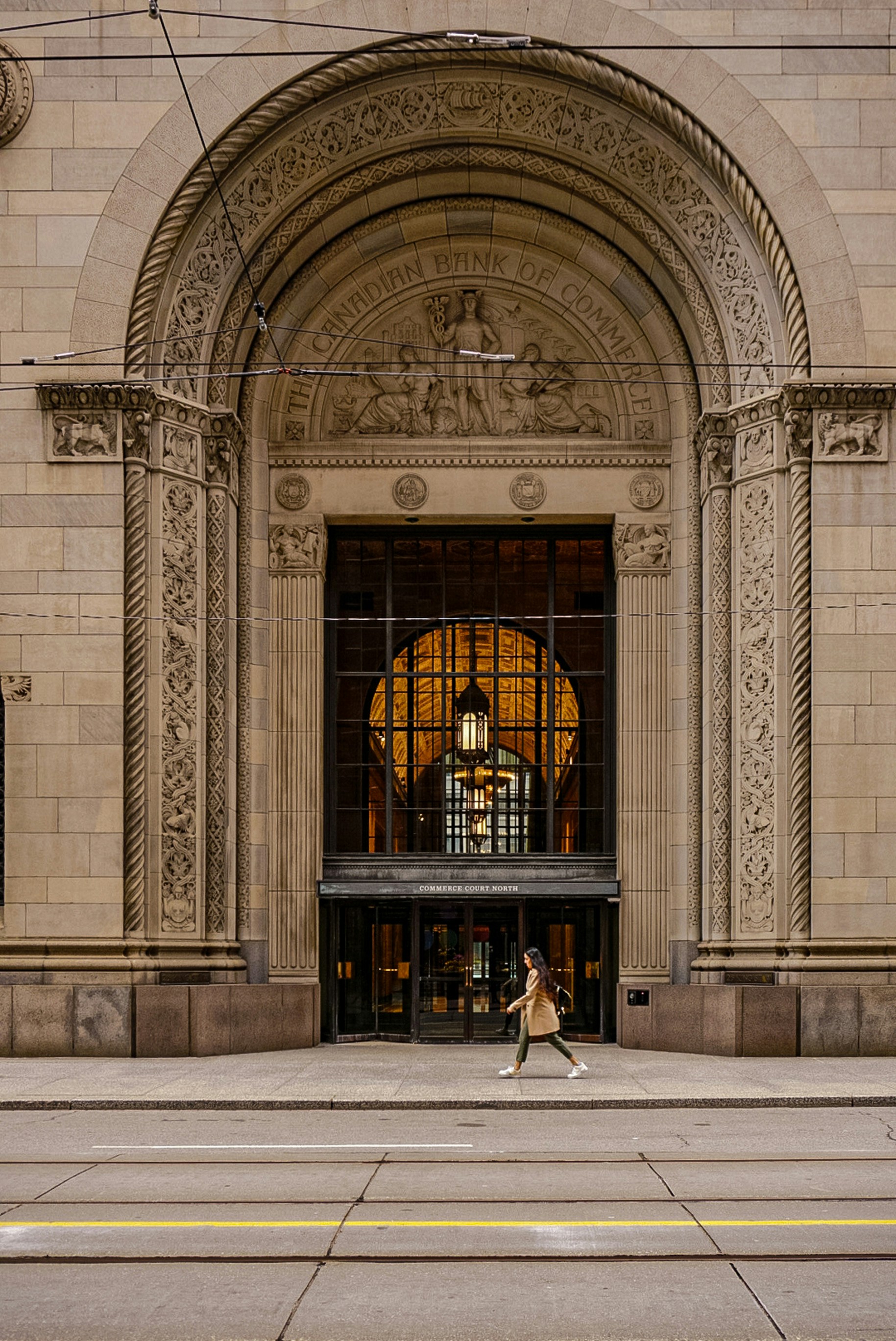 a woman walking down a street past a tall building