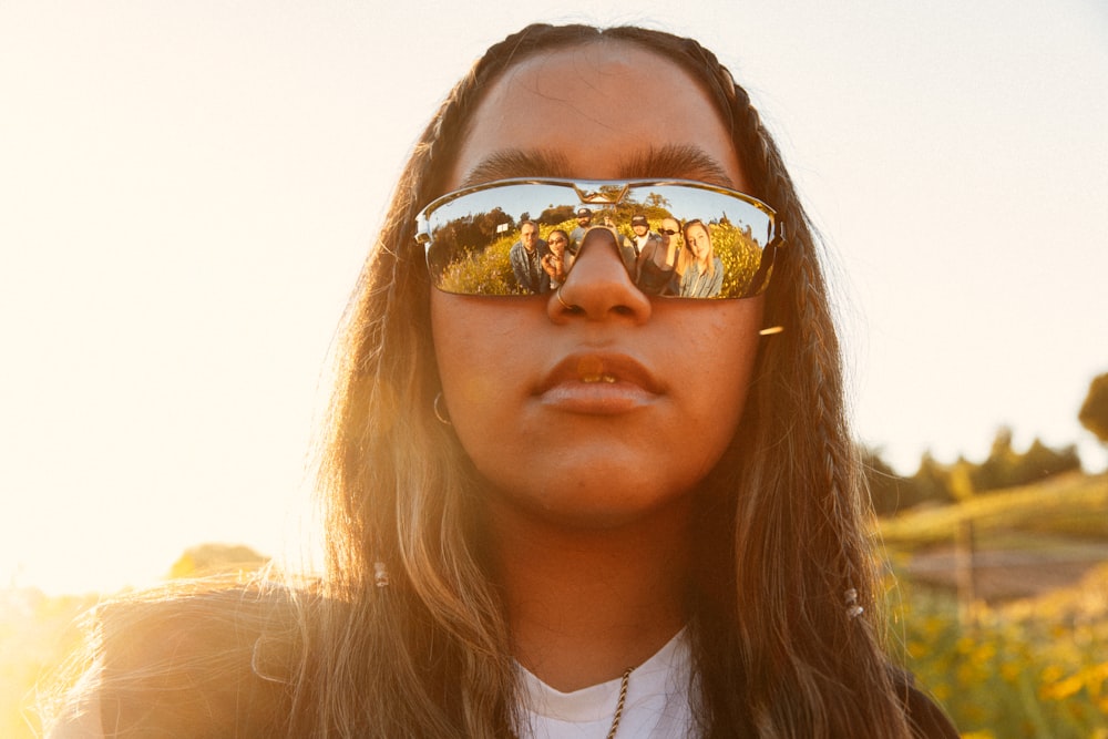 Eine Frau mit langen Haaren, die eine verspiegelte Sonnenbrille trägt