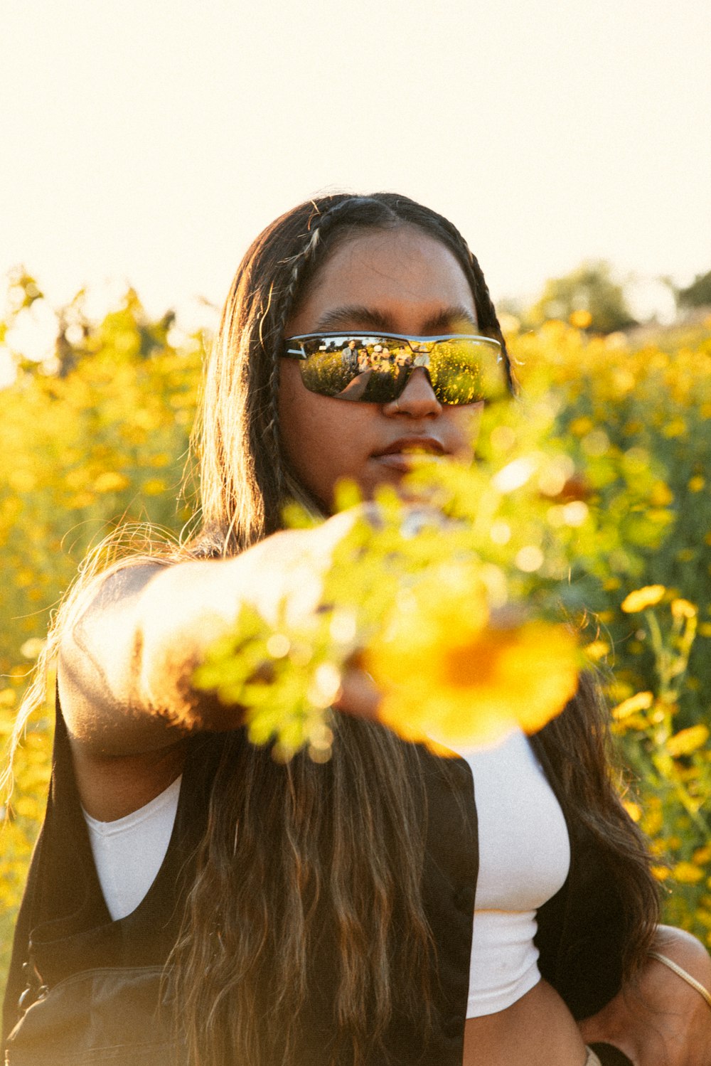 a woman wearing sunglasses standing in a field of flowers