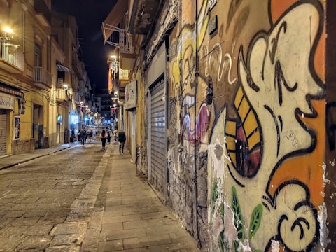 Nighttime street scene in a vibrant Medellín barrio with colorful graffiti and glowing streetlights.