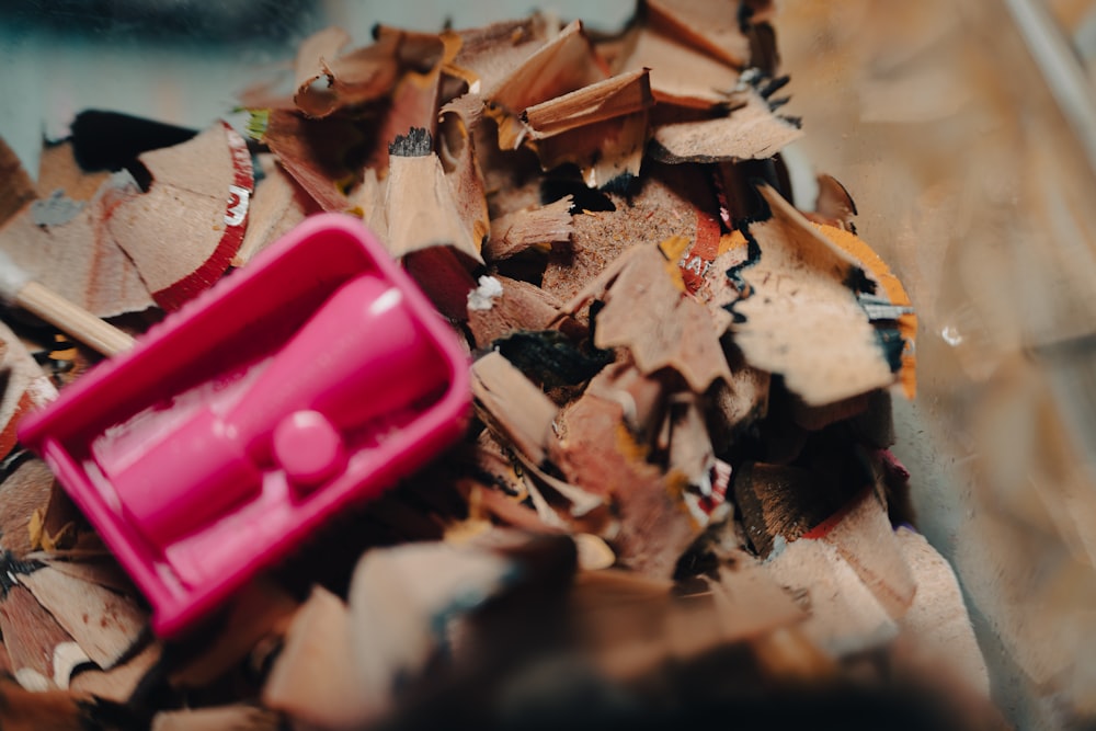 a pile of wood shavings and a pink container