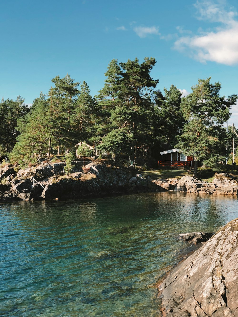 a house on the shore of a lake surrounded by trees