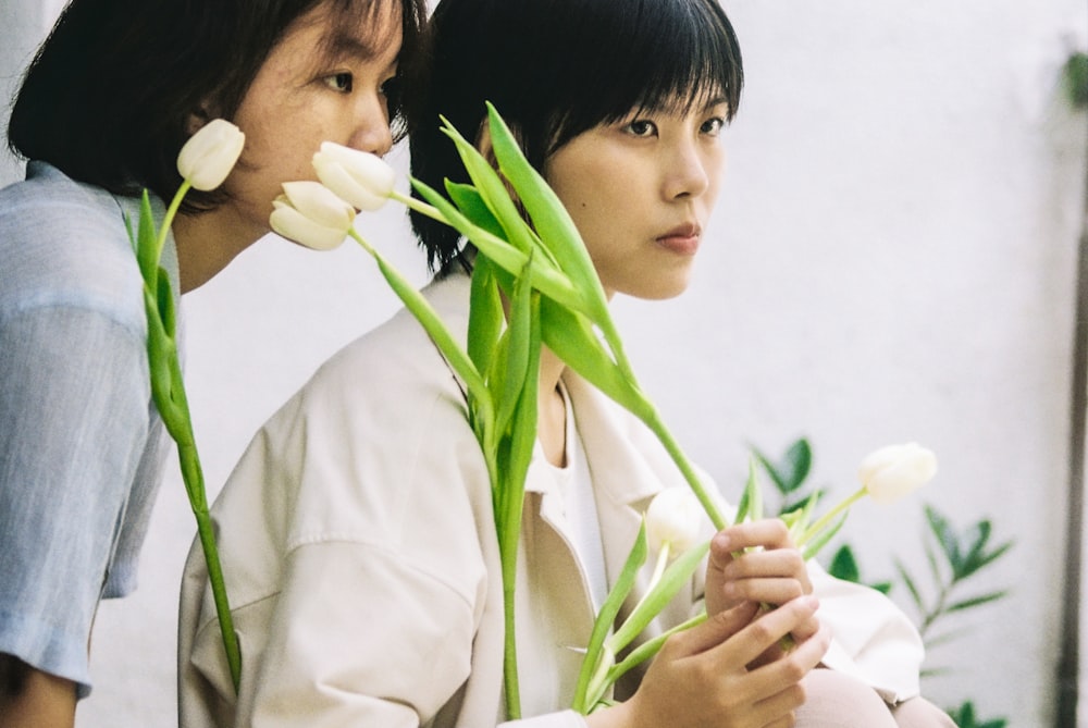 a couple of women standing next to each other holding flowers