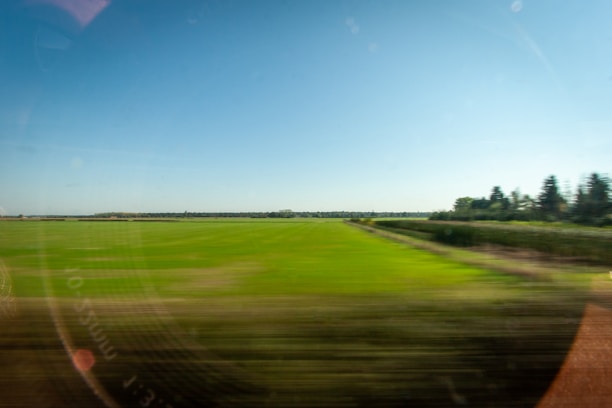Abstract image of green fields beneath a blue sky with biofuel-powered vehicles moving in harmony.