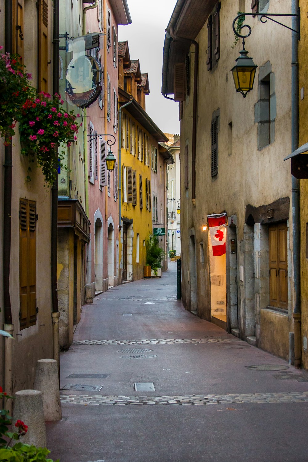 a narrow street with a clock on the side of it