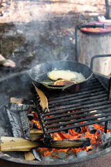 A cast iron skillet with sizzling vegetables over an open flame.