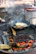A cast iron skillet with golden pancakes cooking on a rustic wooden table.
