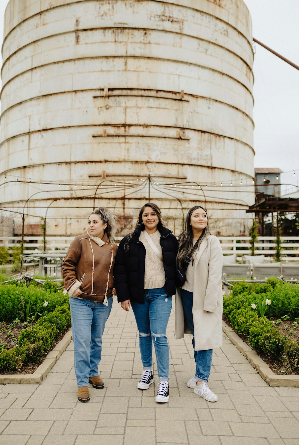 three women standing in front of a large water tank