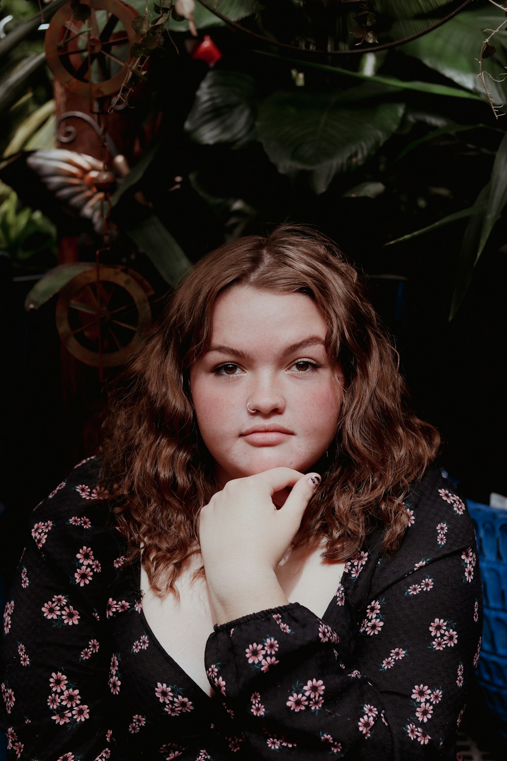 a woman sitting in front of a potted plant