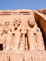 two large statues of pharaohs in front of a building