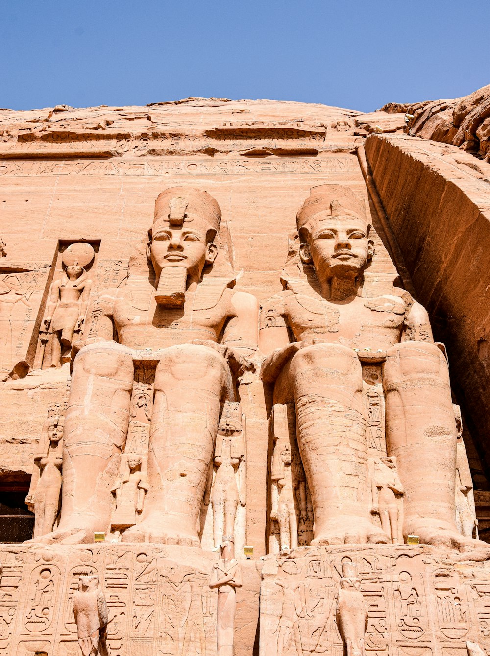 Deux grandes statues de pharaons devant un bâtiment