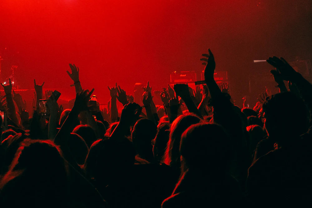Yleisön kädet kohoavat konsertin punaisessa lavavalossa