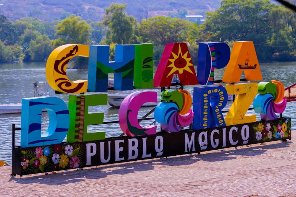 a colorful sign that says happy birthday in front of a body of water