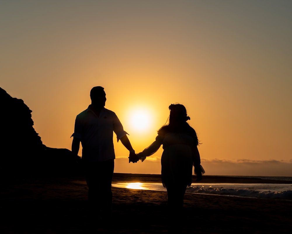 a man and a woman hold hands as the sun sets