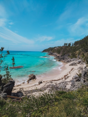 A serene beach view of Fernando de Noronha with crystal-clear turquoise waters and rocky cliffs.