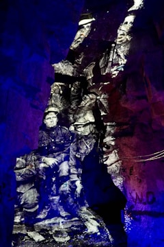 Black and white image of soldiers appears projected onto rough, rocky cave walls, creating a historical and ghostly effect. The distinct contrast between the monochrome figures and the vibrant blue and purple lighting surrounding them creates a surreal, immersive environment.