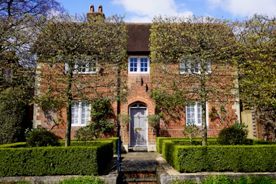 A charming two-story brick townhouse with a well-kept front garden.