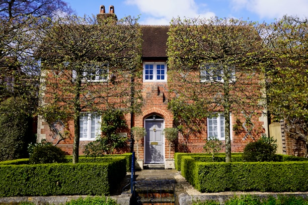 A charming two-story brick home with a well-manicured front yard and large windows letting in natural light.