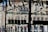 Glass shelves display bags filled with dark chocolates tied with ribbons. The scene is set against a backdrop of an old European building with arched windows and intricate architectural details.