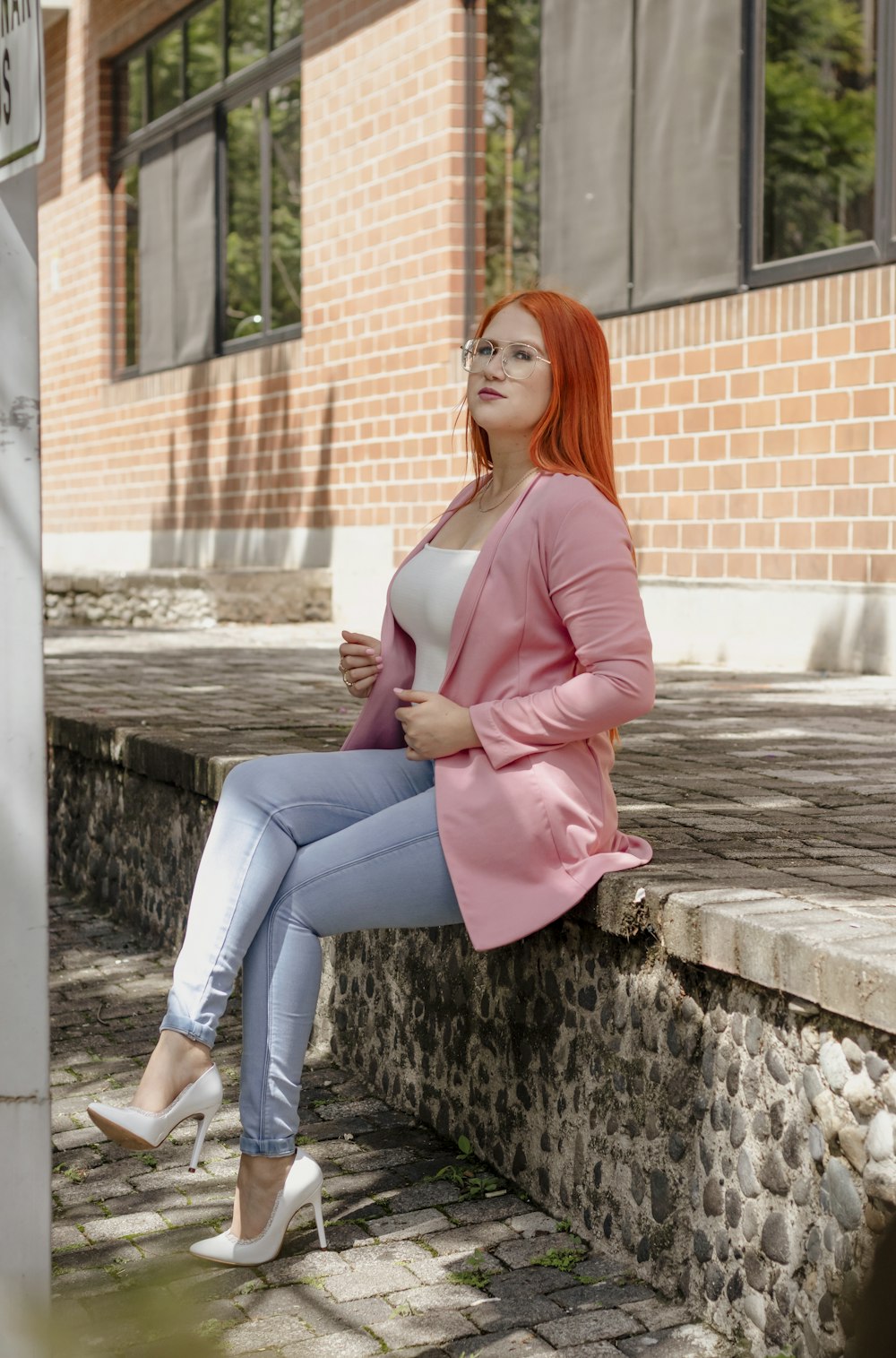 a woman with red hair is sitting on a ledge