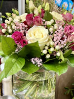 A vibrant bouquet of hybrid roses in a vase, enhanced by the natural scent spray.