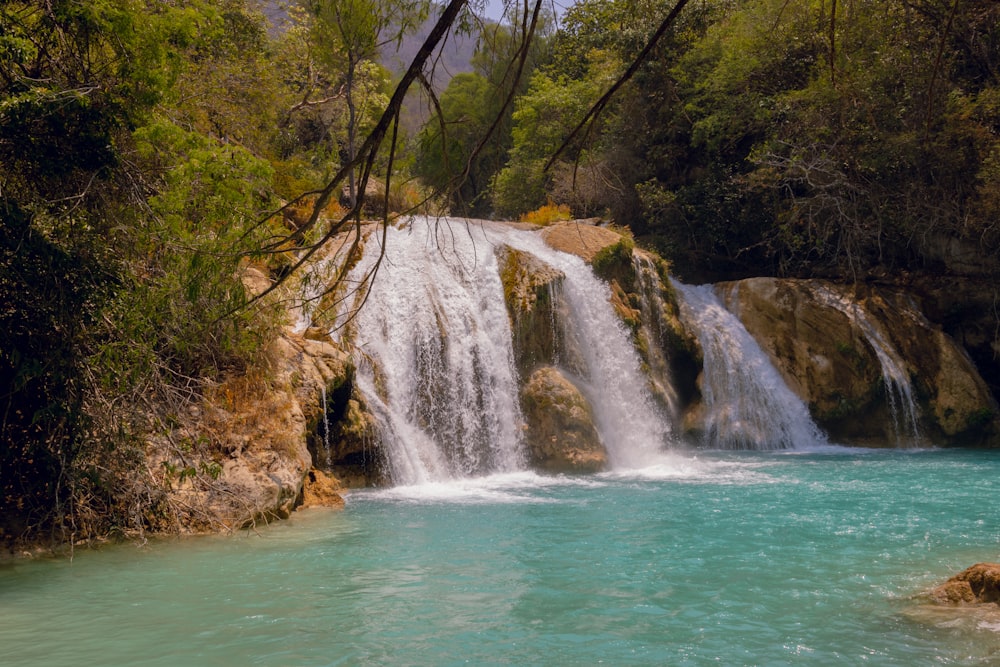 a large waterfall with blue water surrounded by trees