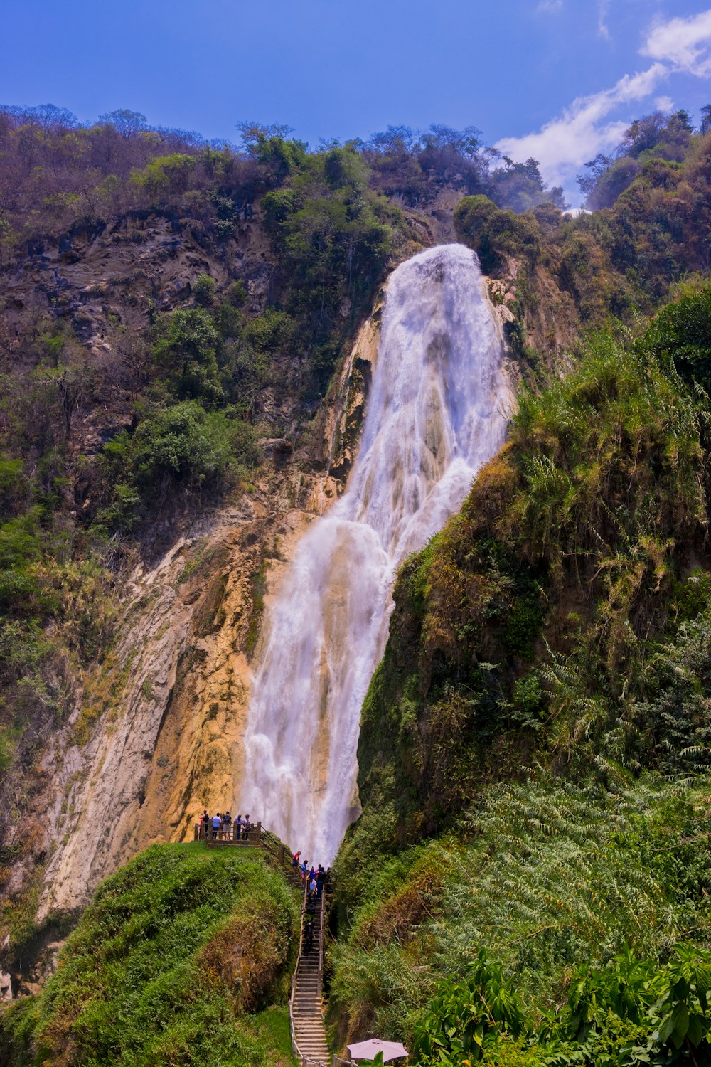 a group of people standing at the base of a waterfall
