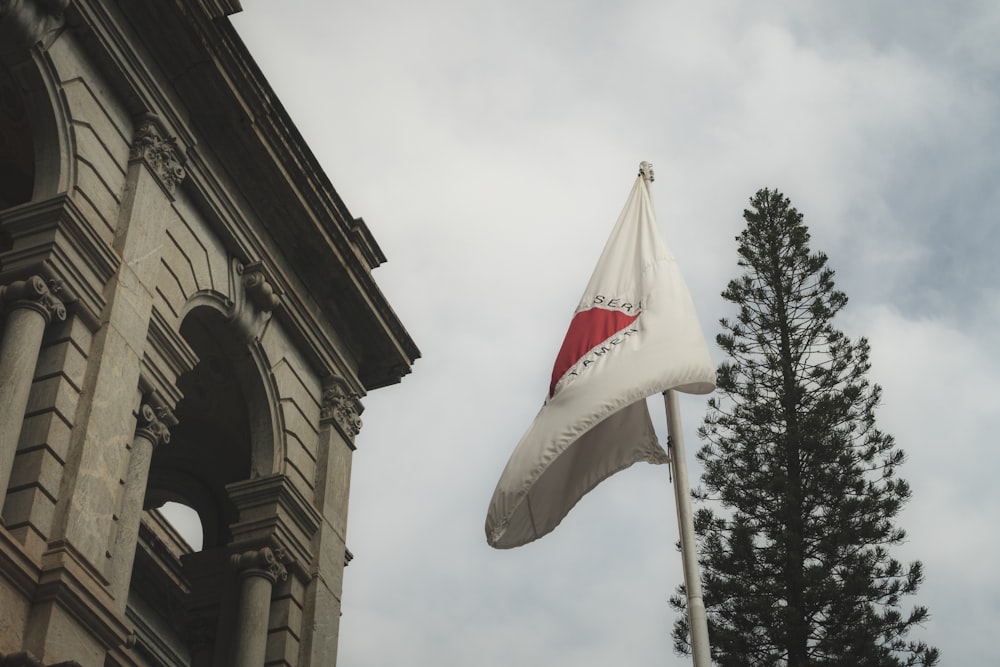 a flag flying in the wind next to a tall building