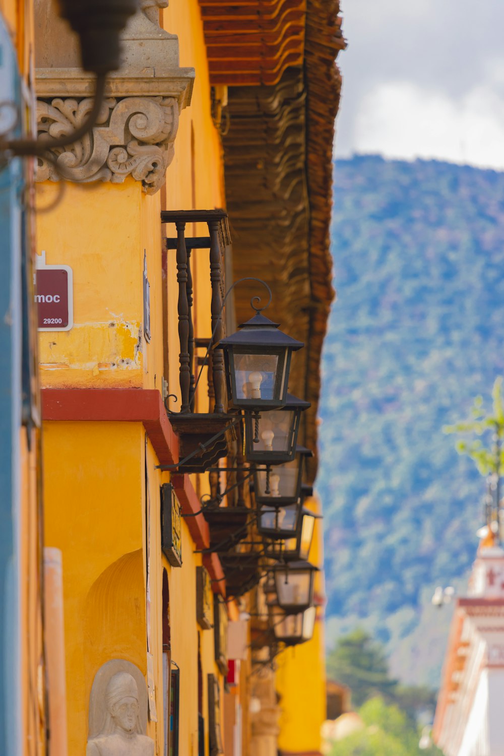 a narrow street lined with yellow buildings with a mountain in the background